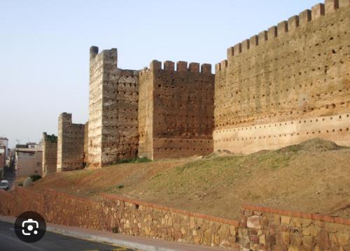 a large brick wall with a hill in front of it at Apartamentos Murallas Merinies in Ceuta