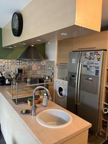 une cuisine avec un évier et un réfrigérateur en acier inoxydable dans l'établissement APPARTEMENT JO, à Saint-Denis