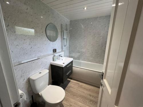 a bathroom with a toilet and a sink and a tub at 3 bedroom sleeps 4 in Glenrothes in Fife