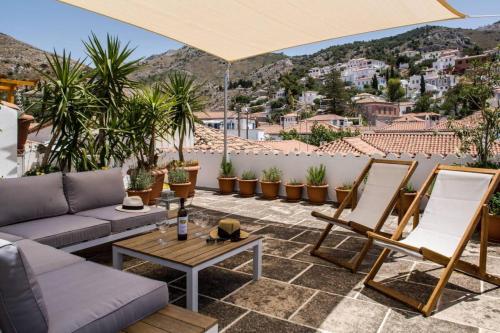 a patio with a couch and chairs and an umbrella at NESEA Boutique Apartments in Hydra