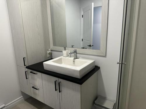 a bathroom with a white sink and a mirror at Refuge urbain à Beauport in Quebec City