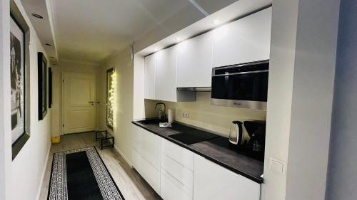 a kitchen with white cabinets and a black counter top at Maison Lily Apartment 4 in Bad Lauterberg
