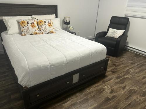 - une chambre avec un lit et une chaise noire dans l'établissement Refuge urbain à Beauport, à Québec
