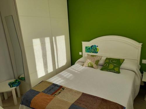 Un pequeño dormitorio con una cama blanca con paredes verdes en La Boquerona en Polanco