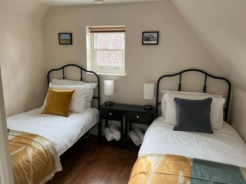 a bedroom with two beds with pillows and a window at Quirky cottage in the historical town of Beverley in Beverley