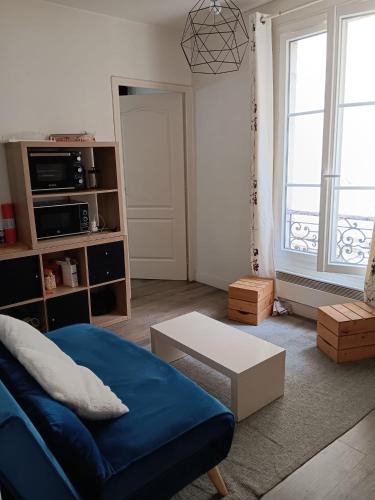salon z niebieską kanapą i stołem w obiekcie Appartement en plein coeur du 10eme et proche de plusieurs Gares w Paryżu