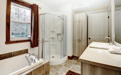 a bathroom with a shower and a tub and a sink at Chalet 9029 Chemin des Alpages by Les Chalets Alpins in Stoneham