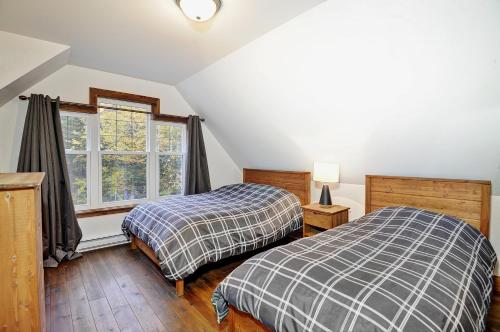 two beds in a room with a window at Chalet 9029 Chemin des Alpages by Les Chalets Alpins in Stoneham