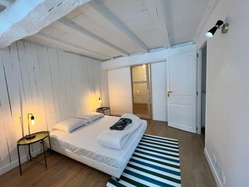 une chambre avec un grand lit blanc et un tapis rayé dans l'établissement Maison de ville rénovée à 5 mn du Futuroscope, à Jaunay-Clan