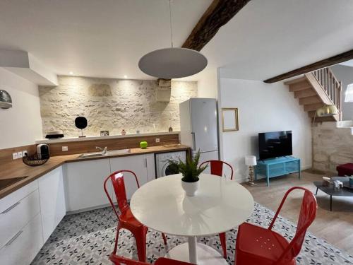 une cuisine avec une table blanche et des chaises rouges dans l'établissement Maison de ville rénovée à 5 mn du Futuroscope, à Jaunay-Clan