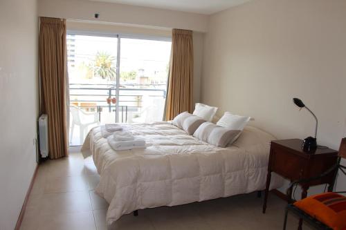 a bedroom with a white bed with a large window at Carol 1 in Salta