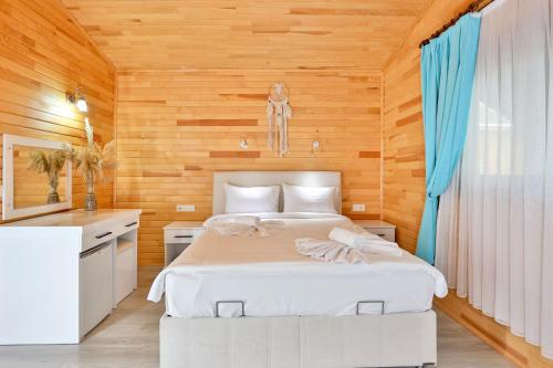 a bedroom with a white bed and a wooden wall at Simge Pension in Cıralı