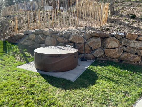 a bath tub sitting in the grass next to a stone wall at Chalet Schäftal in Langau