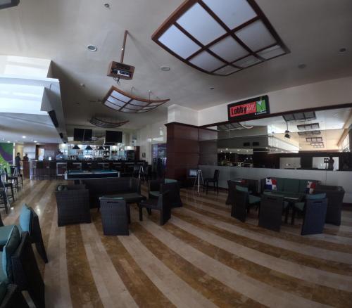 a restaurant with black chairs and tables and a bar at Radisson Colon 2,000 Hotel & Casino in Colón