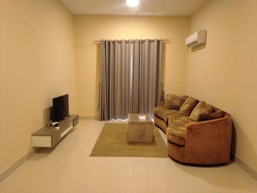 a living room with a couch and a television at Star Dubai Apartment in Salalah