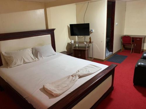 a bedroom with a large white bed with a television at Hotel La Rochelle in Bonamakolo