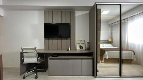 a room with a desk with a television and a chair at Studio Batel com ótima localização in Curitiba