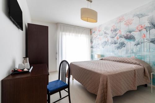 a bedroom with a bed and a table and a window at Hotel Sorriso in Venice-Lido