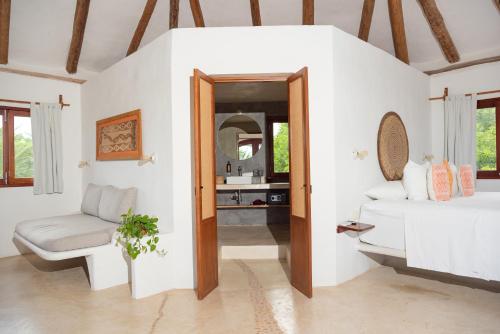 a bedroom with a bed and a chair and a mirror at Casa Takywara in Holbox Island