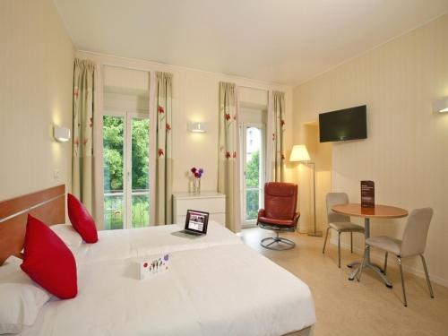een slaapkamer met een groot wit bed en een laptop. bij Hotels & Résidences - Les Thermes in Luxeuil-les-Bains