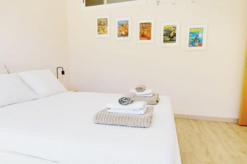 ein weißes Bett mit Handtüchern und Bildern an der Wand in der Unterkunft T2 Sesimbra a 100mts da Praia c/ Piscina in Sesimbra