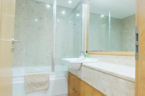 ein weißes Bad mit einem Waschbecken und einer Dusche in der Unterkunft T2 Sesimbra a 100mts da Praia c/ Piscina in Sesimbra