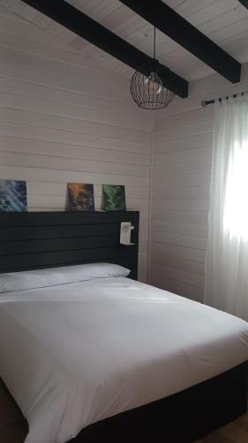 sypialnia z dużym białym łóżkiem i żyrandolem w obiekcie La cabaña de Uceda w mieście Uceda