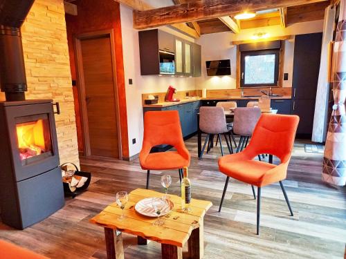 a living room with orange chairs and a fireplace at "Le Cabanon cendré" petit chalet cosy au coeur de Gérardmer in Gérardmer