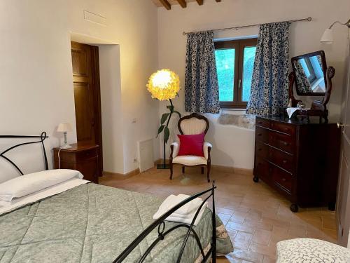 a bedroom with a bed and a tv and a chair at Il Nido del Falco nelle Antiche Mura in Saturnia