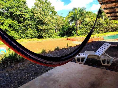 a hammock with a chair and a pool at Kocorica in Parrita