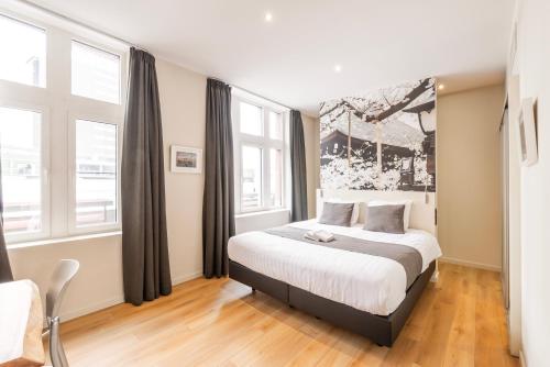 a bedroom with a bed in a room with windows at Hotel Het Menneke in Hasselt