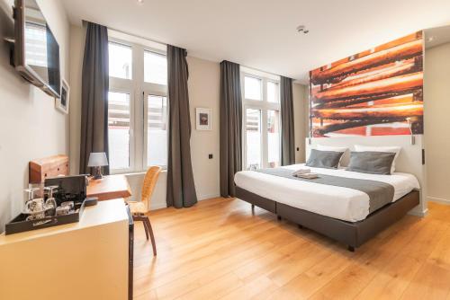 a bedroom with a bed and a desk and windows at Hotel Het Menneke in Hasselt
