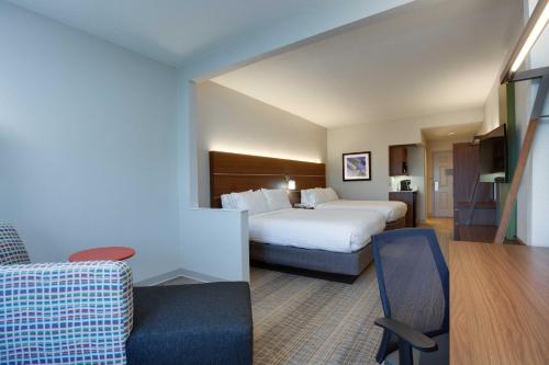 a hotel room with a bed and a chair at Holiday Inn Express & Suites Orlando International Airport by IHG in Orlando