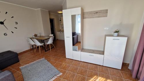 a living room with a table and a clock on the wall at Silence Apartmanház Zalakaros in Zalakaros