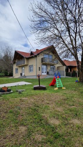 a yard with playground equipment in front of a house at Silence Apartmanház Zalakaros in Zalakaros
