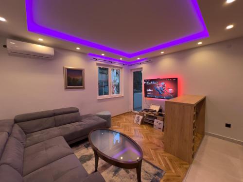 een woonkamer met een bank en een flatscreen-tv bij City Gem: Stylish Urban Hideout in Budva