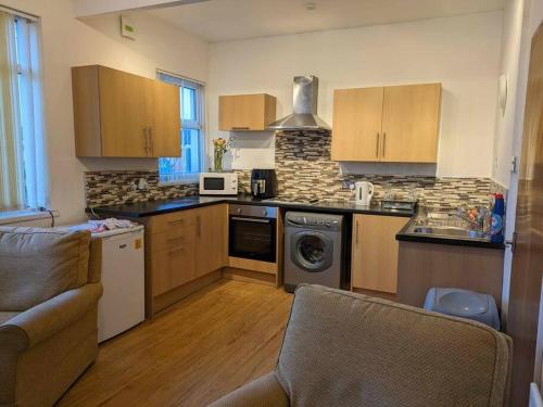 cocina con armarios de madera, lavadora y secadora en Cozy flat en Newport