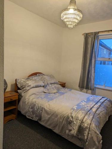 een slaapkamer met een bed, een kroonluchter en een raam bij Cozy flat in Newport