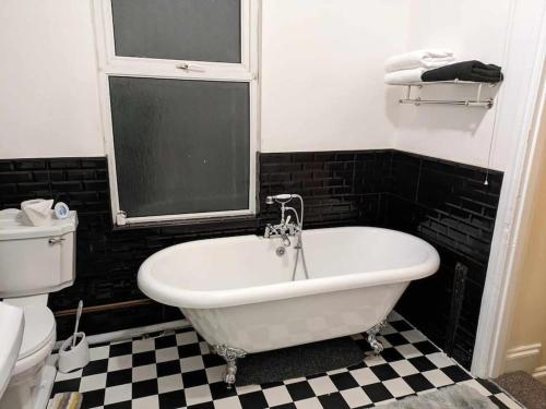 een wit bad in een badkamer met een geruite vloer bij Cozy flat in Newport