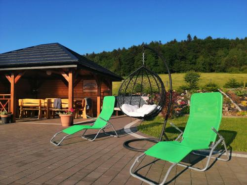 two green chairs and a swing on a patio at Agroturystyka Szklana Polana in Huta Szklana