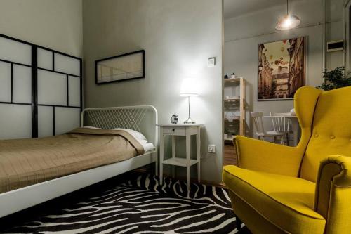 um quarto com uma cama e uma cadeira amarela em Cosy Apartment In Party District K30 em Budapeste