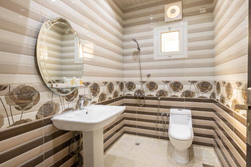 a bathroom with a sink and a toilet and a mirror at Al-Jamwaut A - Qaswarah Residence in Al Madinah