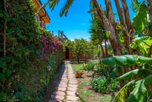 a garden path in front of a house with flowers at Villa del Papiro Charme Apartments in Avola