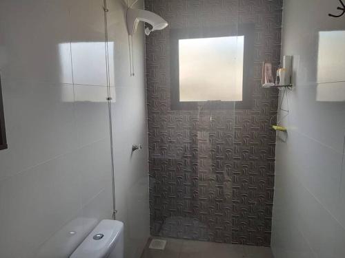 een badkamer met een douche, een toilet en een raam bij Casa a 550m da praia e 350m da Lagoa da Tapera. in Passo de Torres