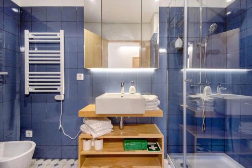 a blue tiled bathroom with a sink and a shower at Casa Marques Apartments in Aveiro