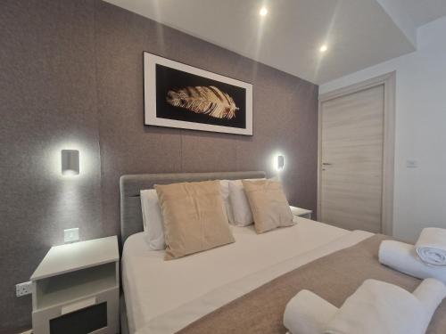 Un dormitorio con una gran cama blanca y una mesa en KORZO SUITES SLIEMA II, en Sliema