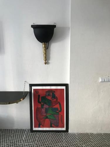 une photo sur un mur avec un pot noir sur un mur dans l'établissement De Balearibus, à Cala Llonga