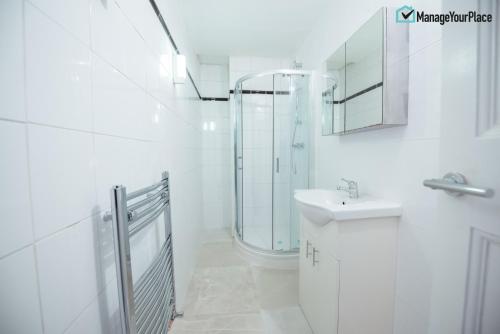 biała łazienka z prysznicem i umywalką w obiekcie Great Central London Flat w Londynie