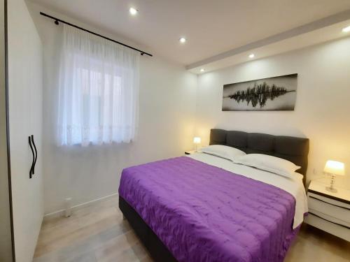 1 dormitorio con cama morada y ventana en Apartments Alfa en Baška