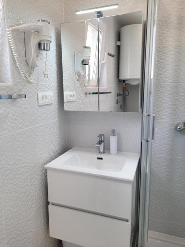 a white bathroom with a sink and a mirror at Apartments Alfa in Baška